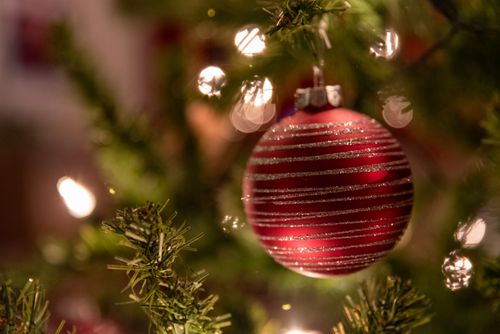 Free Close-up of a red bauble with glitter stripes on a decorated Christmas tree. Stock Photo