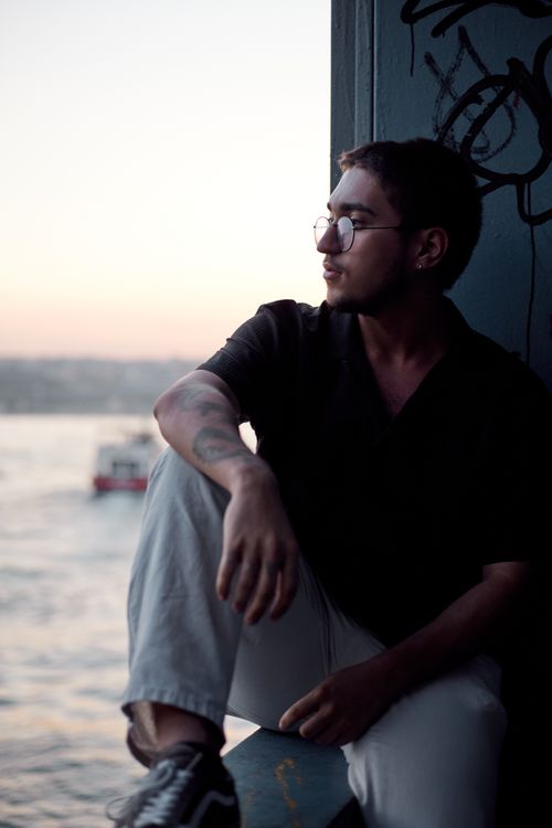 Free Young man in İstanbul relaxing by the Bosphorus at dusk, creating a contemplative mood. Stock Photo