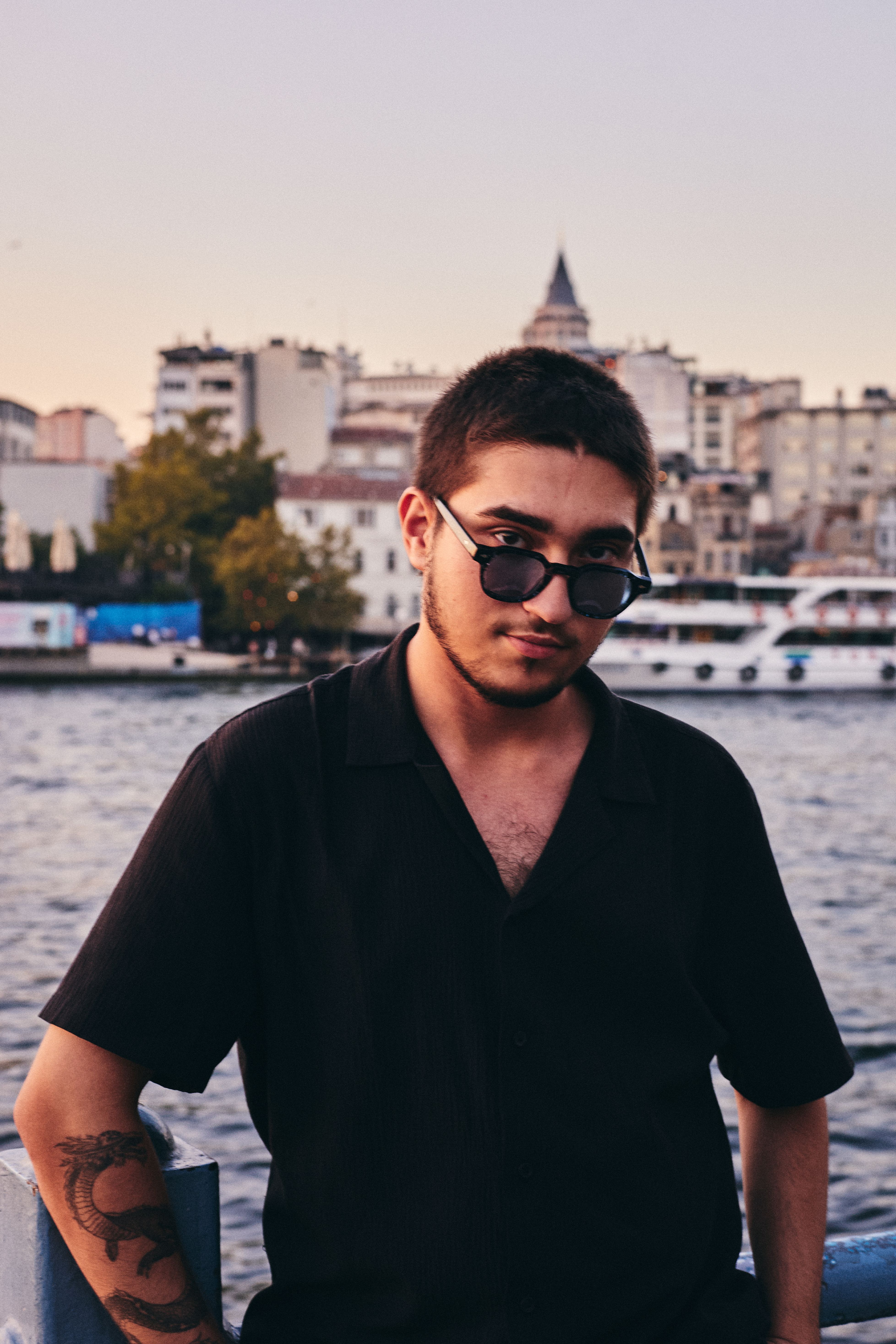 Young man in sunglasses with Galata Tower in the background at sunset in Istanbul.
