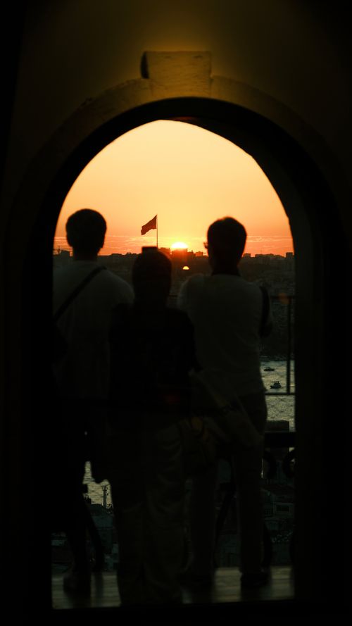 Free Silhouettes of people enjoy a breathtaking sunset view through an arched window. Stock Photo