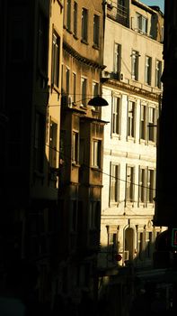 Dramatic sunlight casting shadows in a narrow urban alley with vintage architecture.