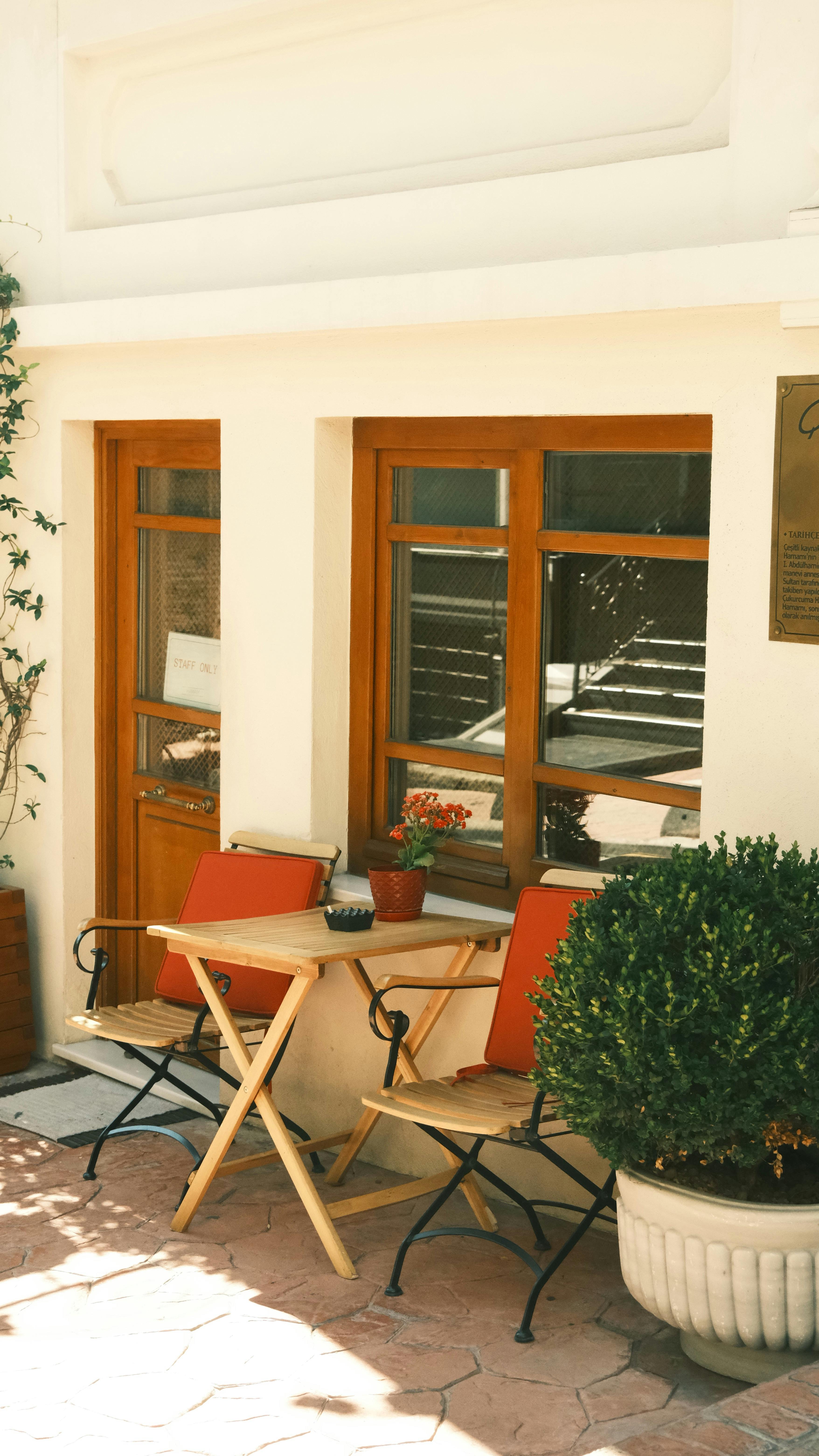 Gratuit O cafenea în aer liber, intimă, cu mobilier din lemn și plante în ghiveci, perfectă pentru o evadare liniștită. Fotografie de stoc