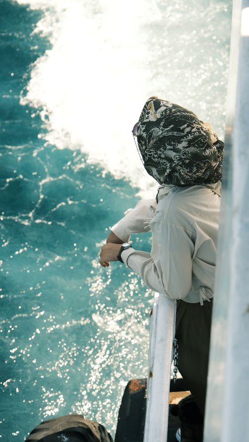 Free A person admiring the ocean view from a ship deck with vibrant water. Stock Photo