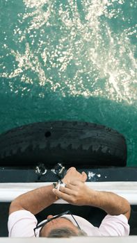 A man enjoys the ocean view from the deck, leaning casually on the rail.