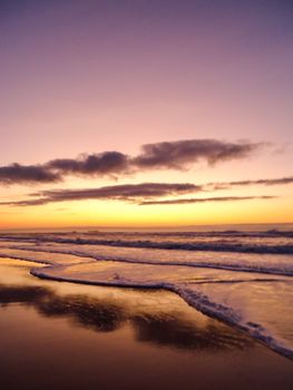 Captivating sunset on a calm beach with waves gently lapping the shore, creating a peaceful atmosphere.
