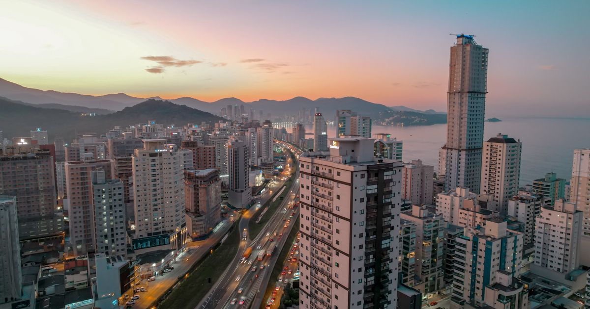 Vista aérea de Itapema, Santa Catarina, ao pôr do sol, mostrando a vibrante paisagem urbana e o litoral.