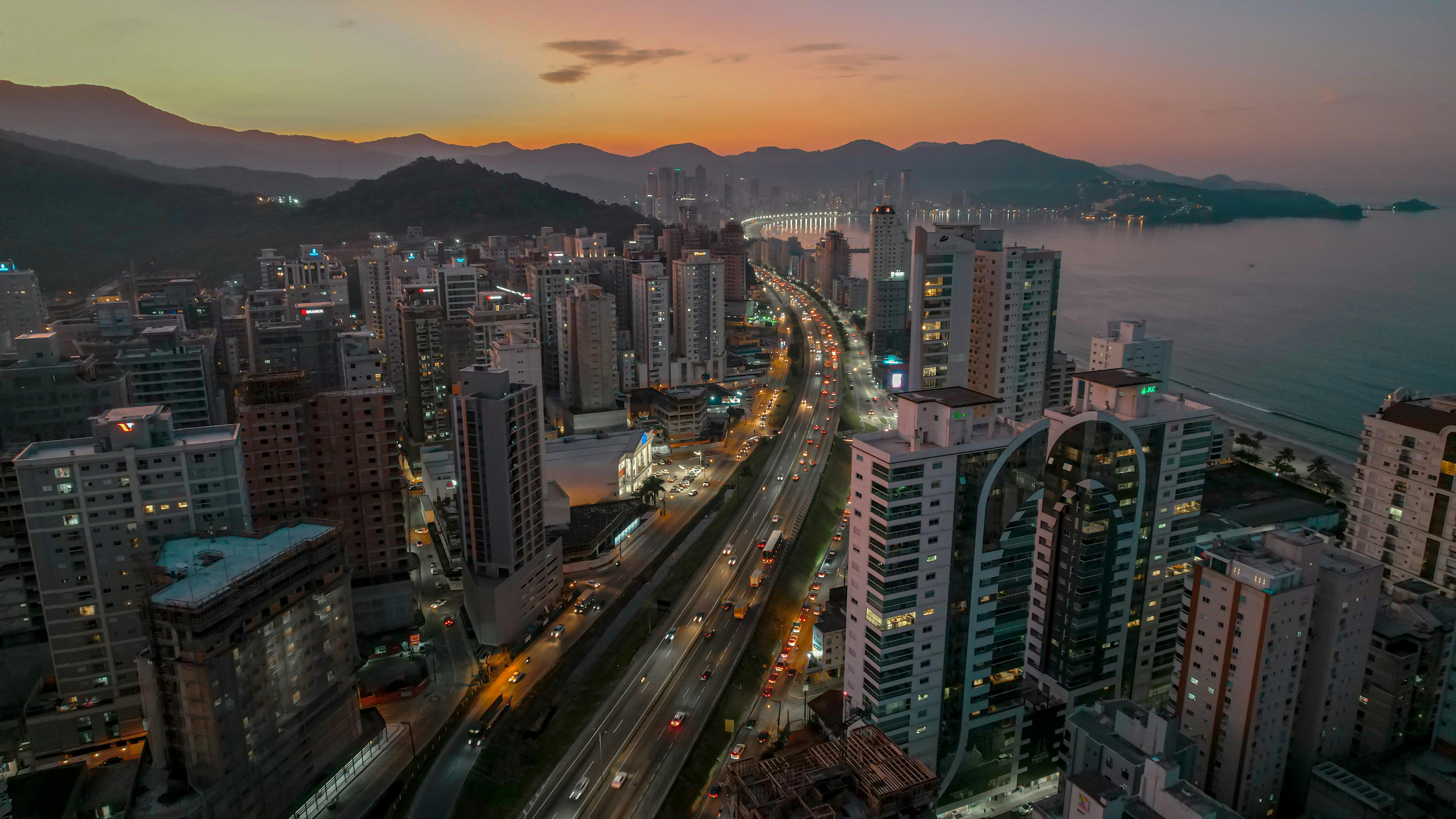 Aerial view of Itapema, Brazil during sunset, showcasing the city lights and coastline.