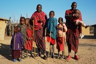 A Maasai family standing outdoors, captured in traditional attire during daylight.