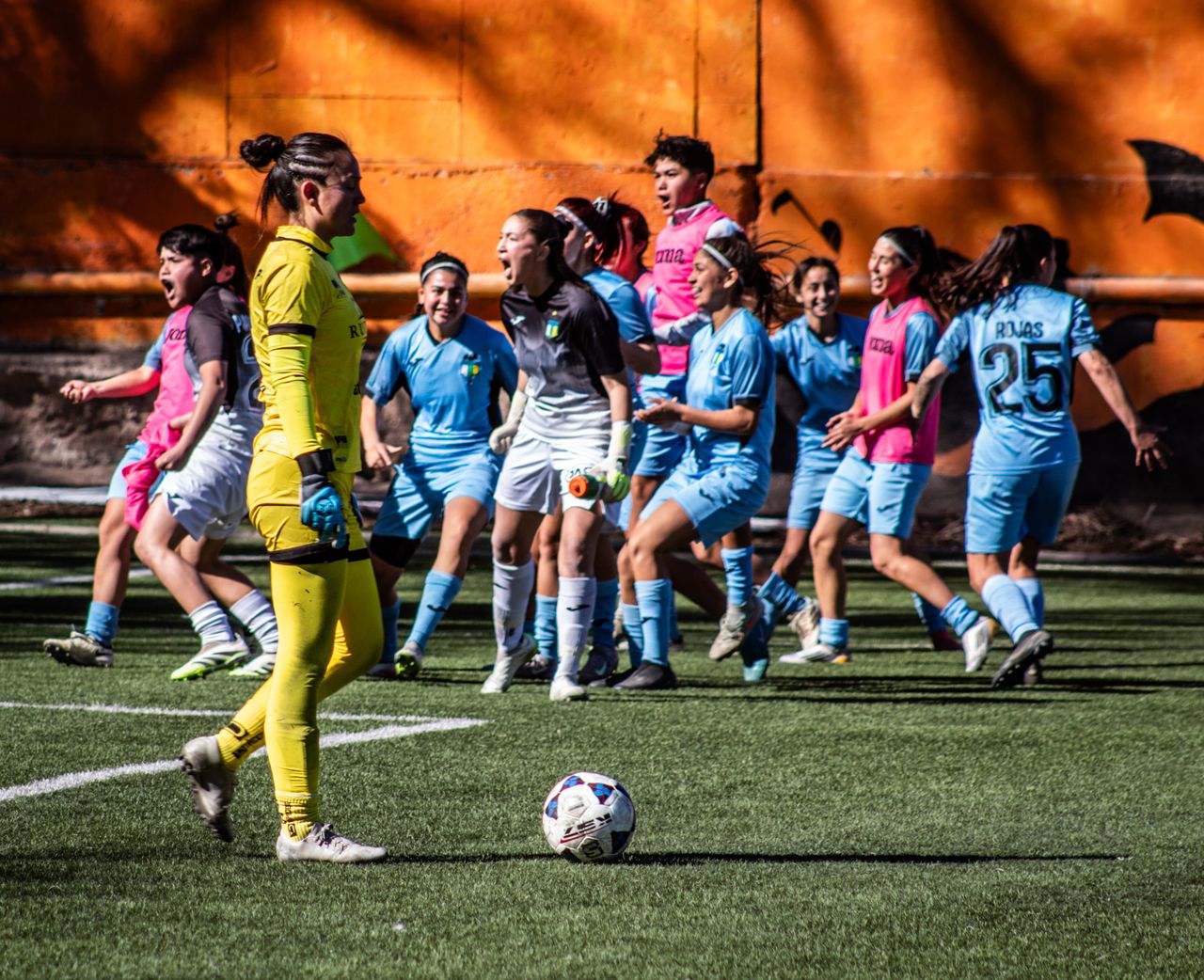 a women s soccer team celebrating after scoring a goal during a daytim