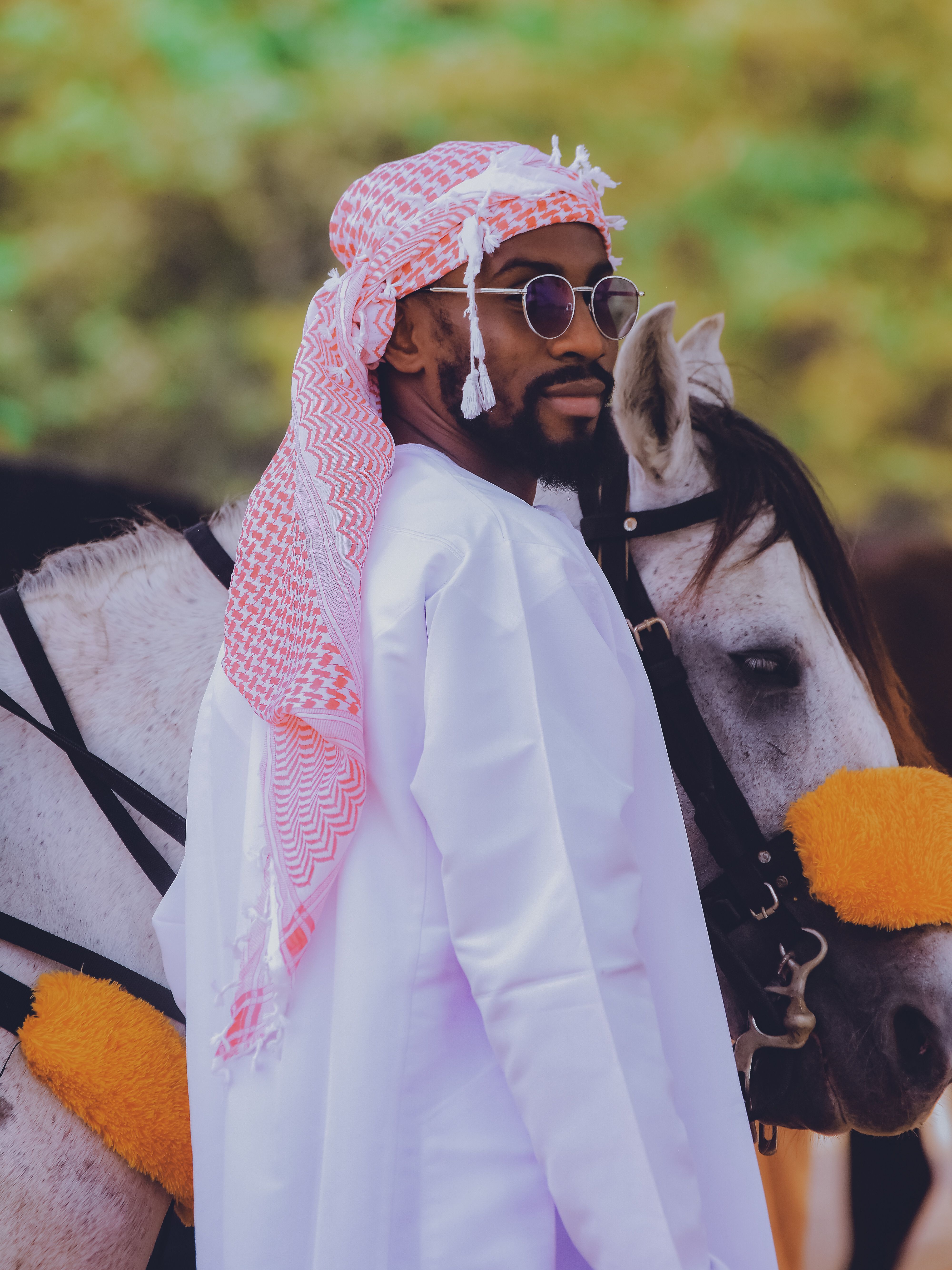 Man in traditional Middle Eastern attire stands beside an Arabian horse in Abuja, Nigeria.