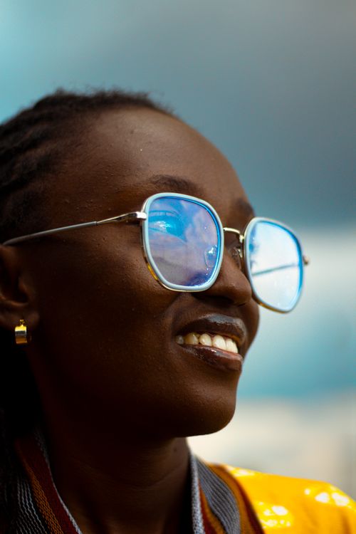 Free Close-up of an adult woman smiling, wearing reflective sunglasses, with sky reflection. Stock Photo