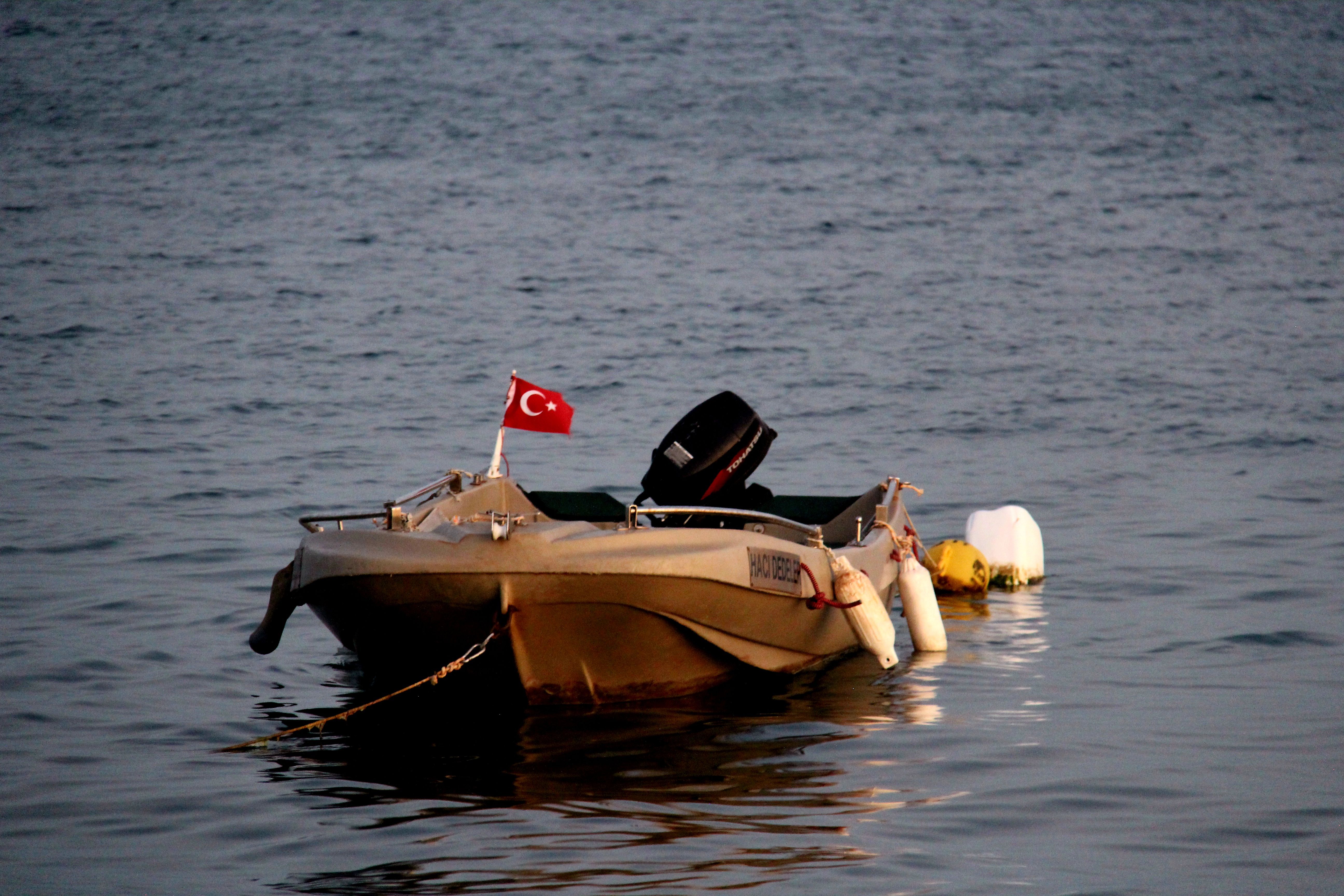 Small boat with a Turkish flag floating on calm water.