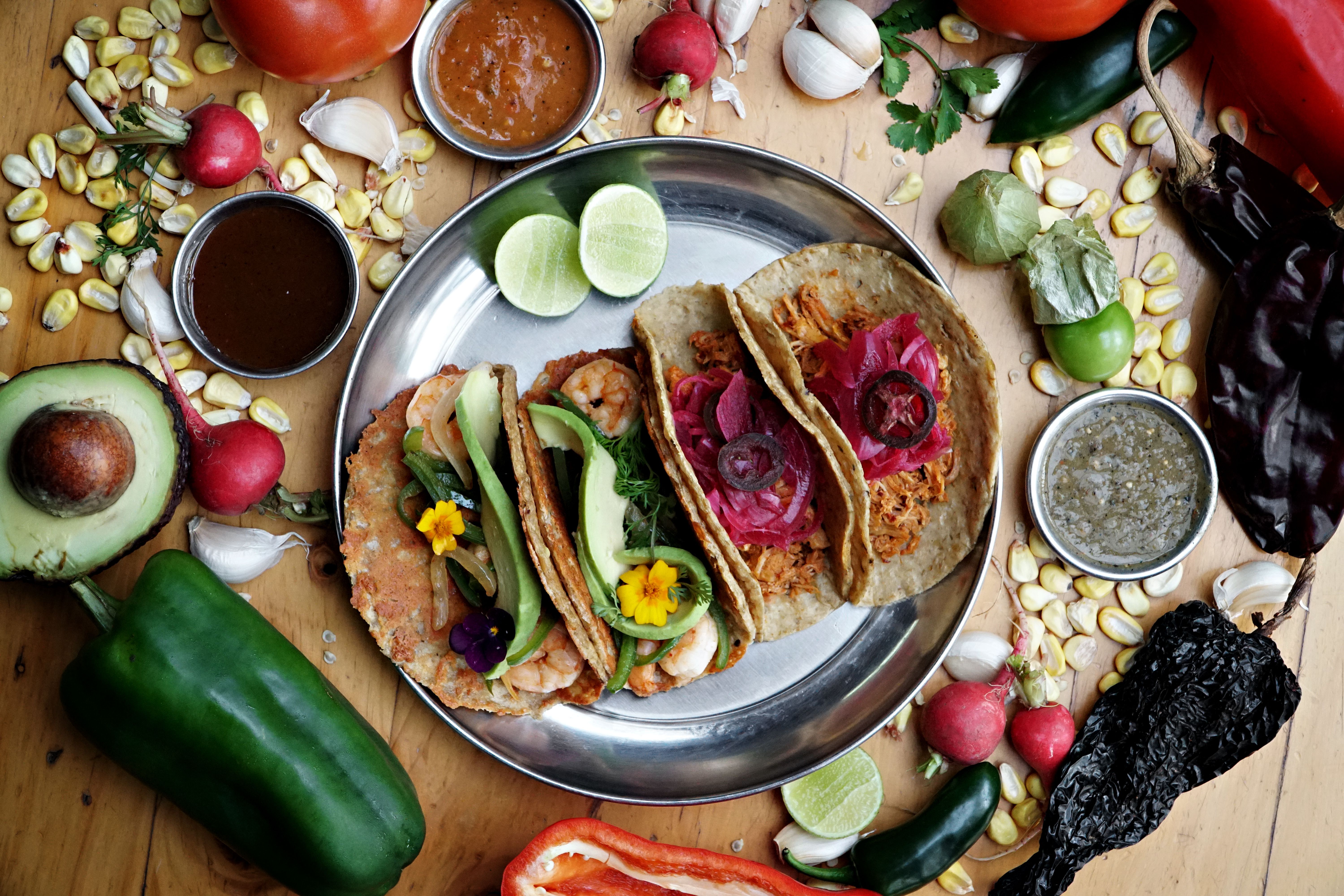 Vibrant Mexican tacos on a platter with fresh vegetables and spices, showcasing traditional culinary art.