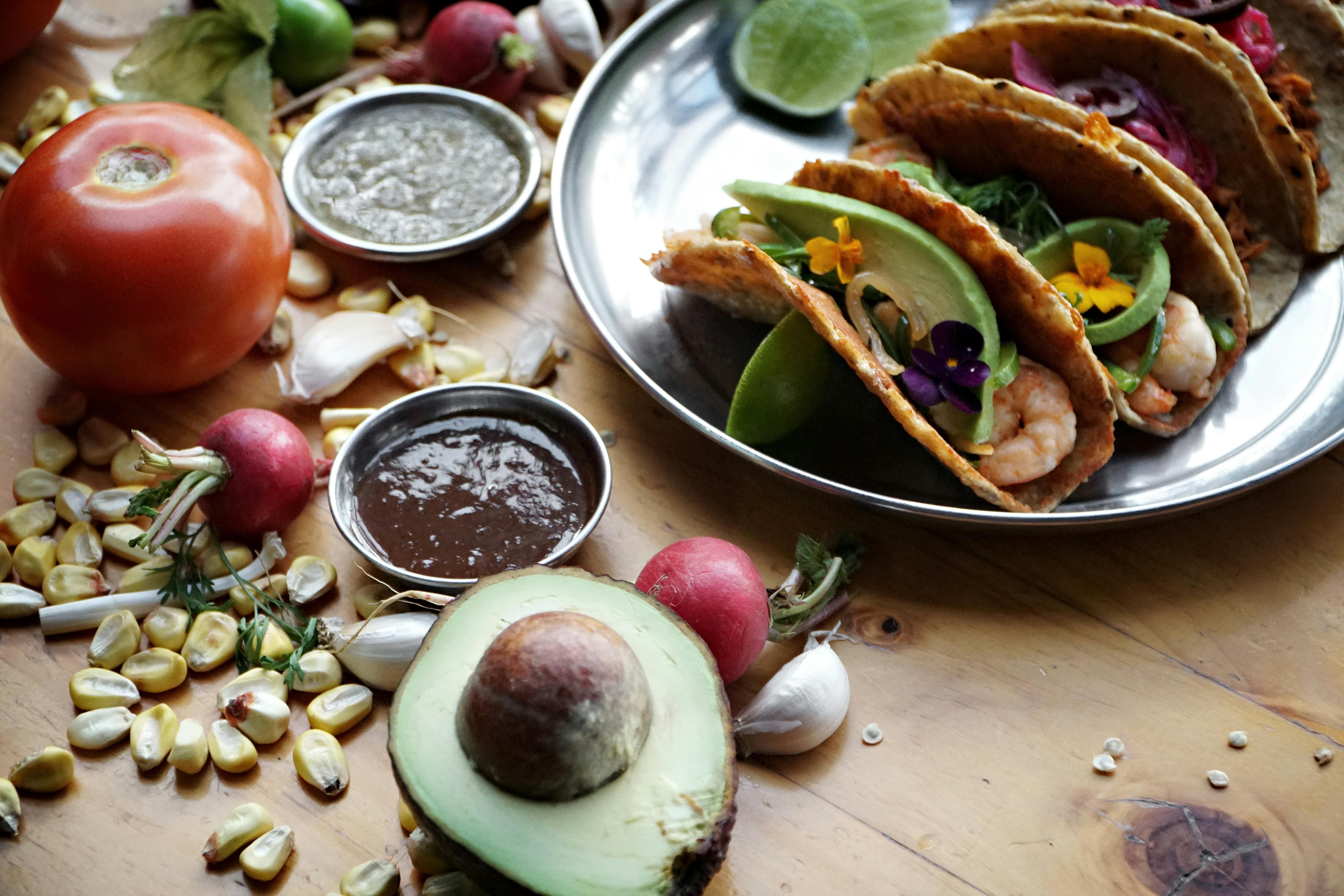 Colorful shrimp tacos with fresh ingredients and vibrant toppings on a wooden table.
