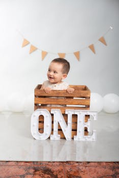 Adorable baby celebrating first birthday with wooden crate and ONE sign.