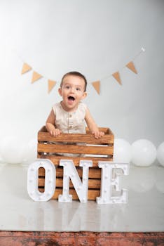 Cute baby celebrating first birthday with wooden crate and balloons.
