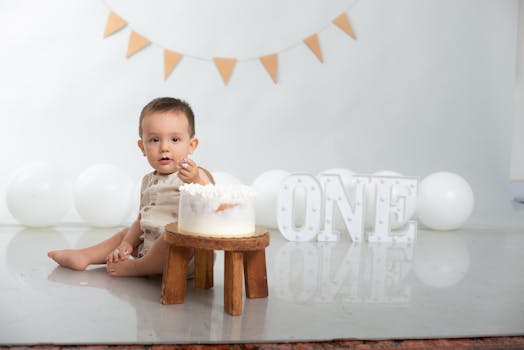 Cute baby celebrating first birthday with cake, balloons, and festive decor.