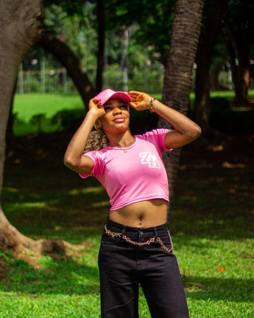 Free Cheerful young woman in pink outfit relishing a sunny day in the park, exuding joy and vitality. Stock Photo