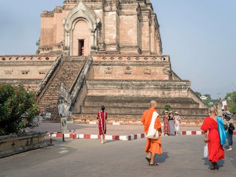 Monks and tourists at Wat Chedi Luang, a historic temple in Chiang Mai, Thailand.