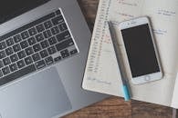 一个配有笔记本电脑、智能手机和木制办公桌上计划器的工作空间，是远程工作的理想选择