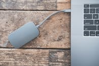 笔记本电脑连接着一个外接硬盘，放在乡村风格的木桌上