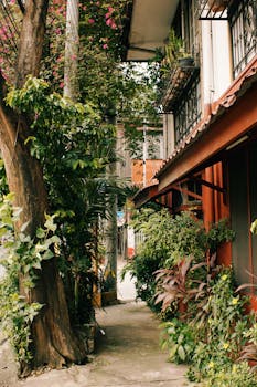 Urban alley with lush plants and colorful flowers, creating a serene and natural environment.
