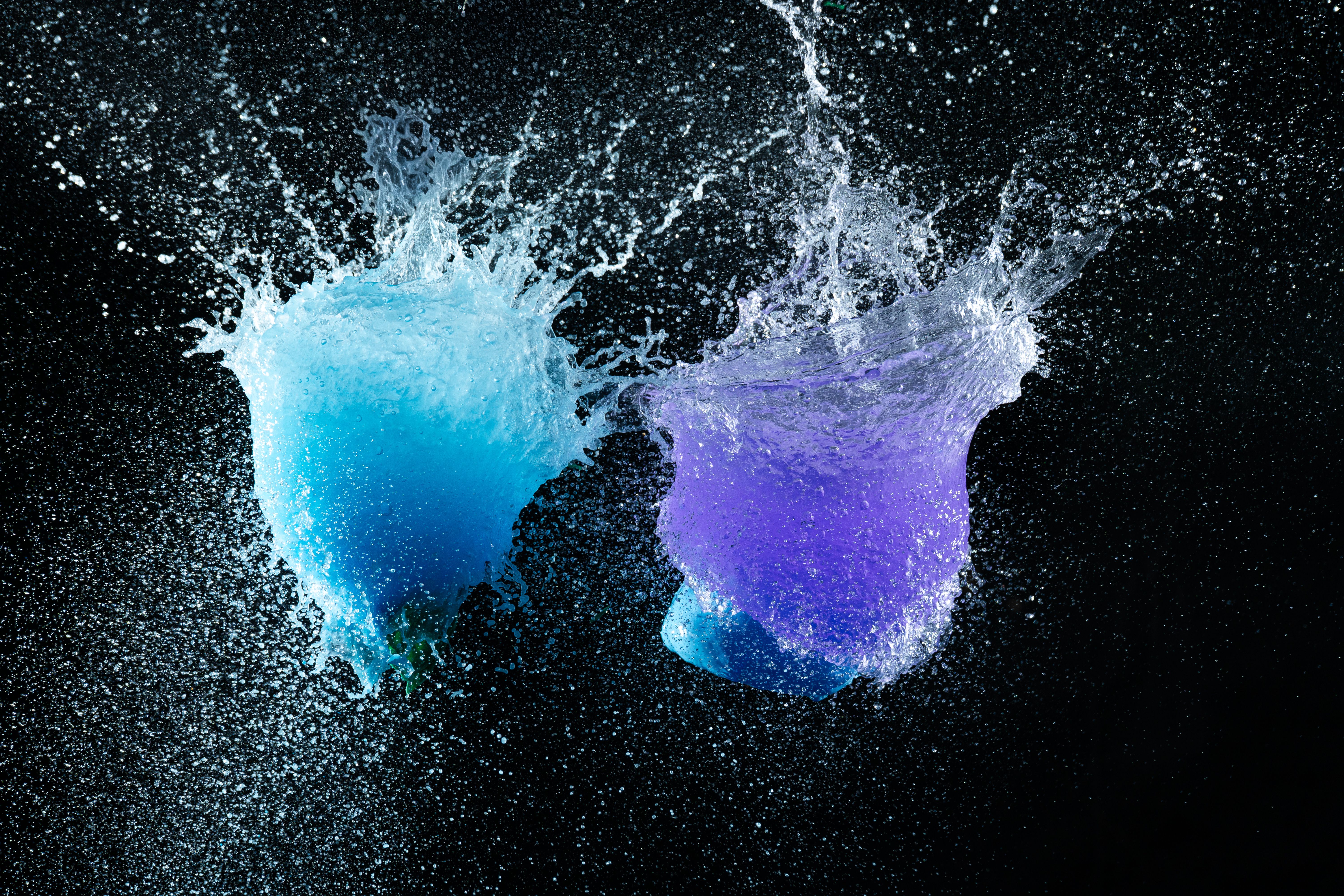 Kostenlos Hochgeschwindigkeitsaufnahme leuchtend blauer und violetter Wasserspritzer auf schwarzem Hintergrund. Stock-Foto