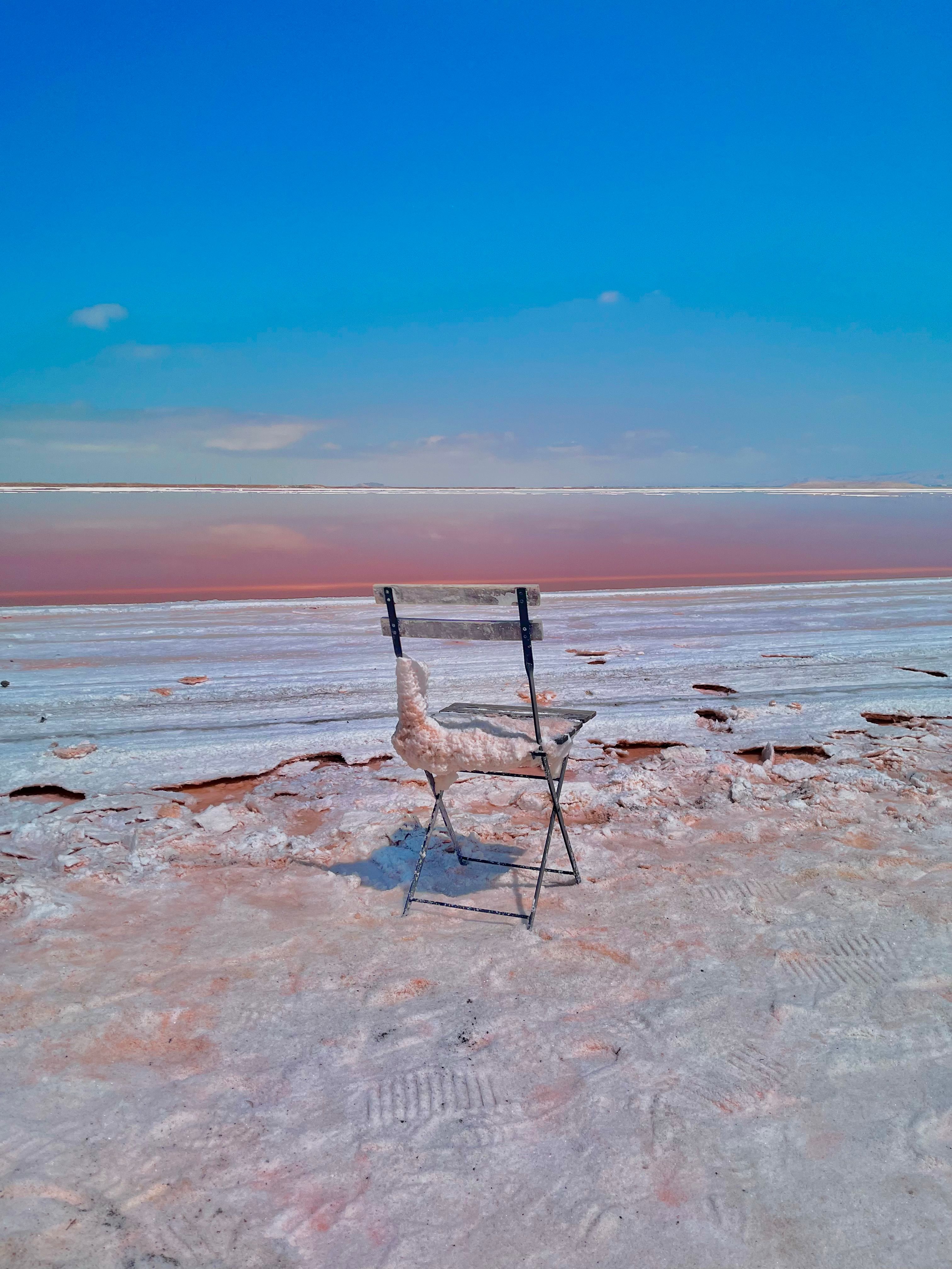A chair sits isolated on the white crusty shore of a vibrant salt lake in San Jose, California.