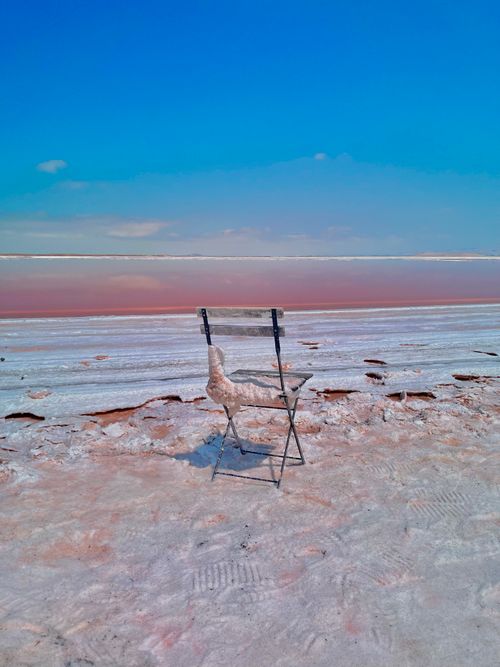 Free A chair sits isolated on the white crusty shore of a vibrant salt lake in San Jose, California. Stock Photo