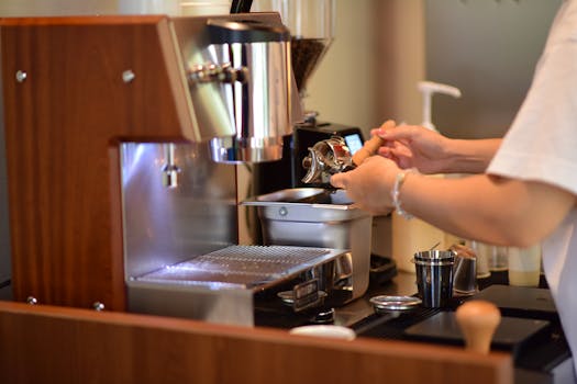 A barista operates an espresso machine, preparing fresh coffee in a cozy café setting.