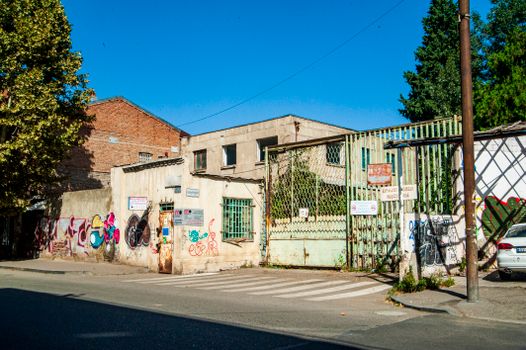 Urban street view featuring graffiti on abandoned buildings under a clear blue sky.