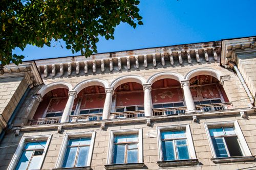 Free A detailed view of a historical building's facade featuring arched windows and classical architecture. Stock Photo