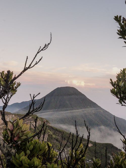 Free Tranquil mountain landscape at sunrise, surrounded by lush greenery and mist. Stock Photo