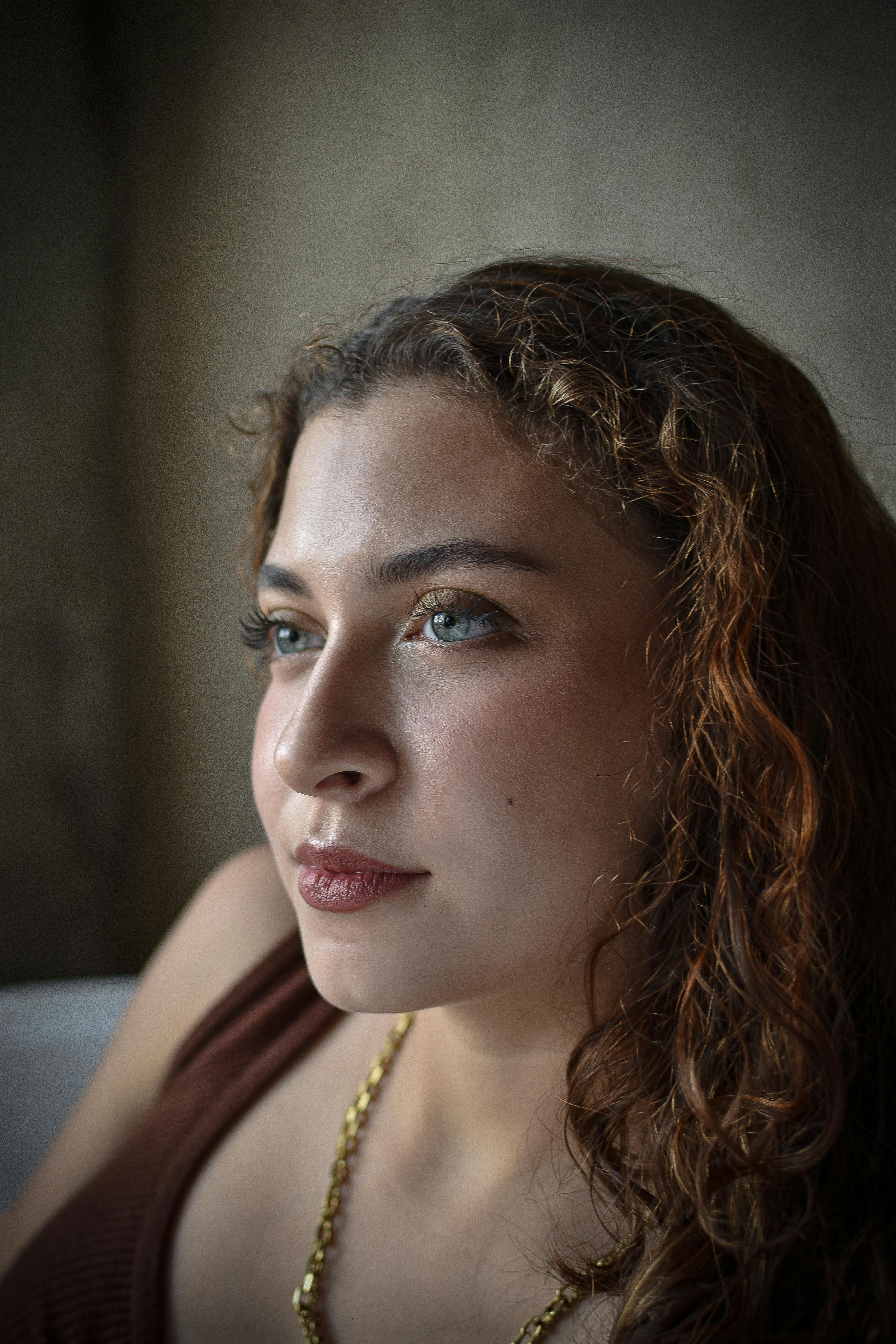 Close-up portrait of a young woman with curly hair and thoughtful expression.