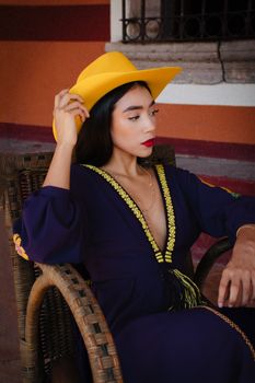 Elegant woman in traditional dress with a yellow hat in León, Mexico.