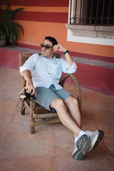 Man sitting on a wicker chair, holding a camera in León, Mexico.