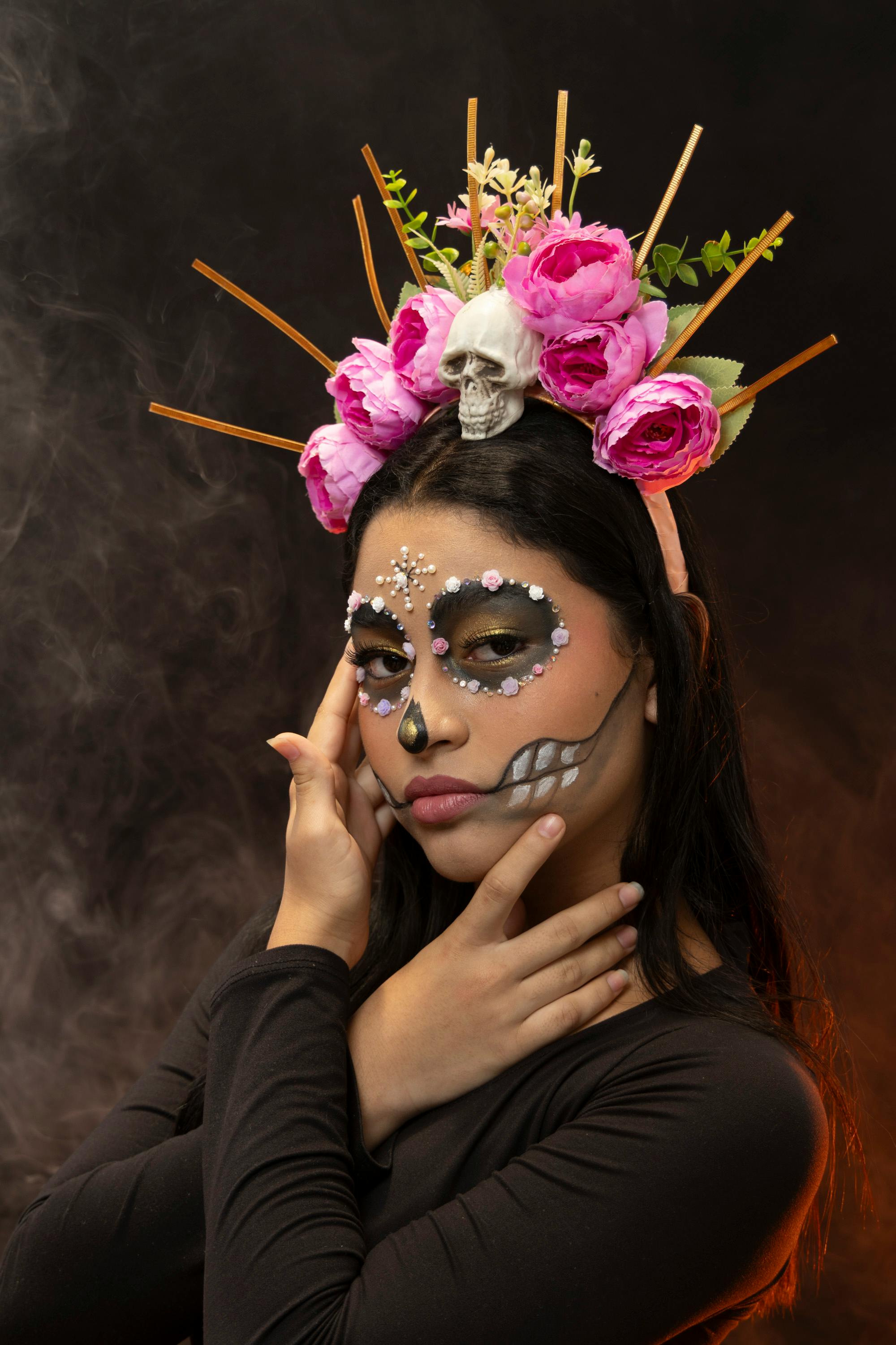 Gratis Ritratto di una donna con trucco Catrina e un copricapo floreale a forma di teschio, su uno sfondo nero fumo. Foto a disposizione