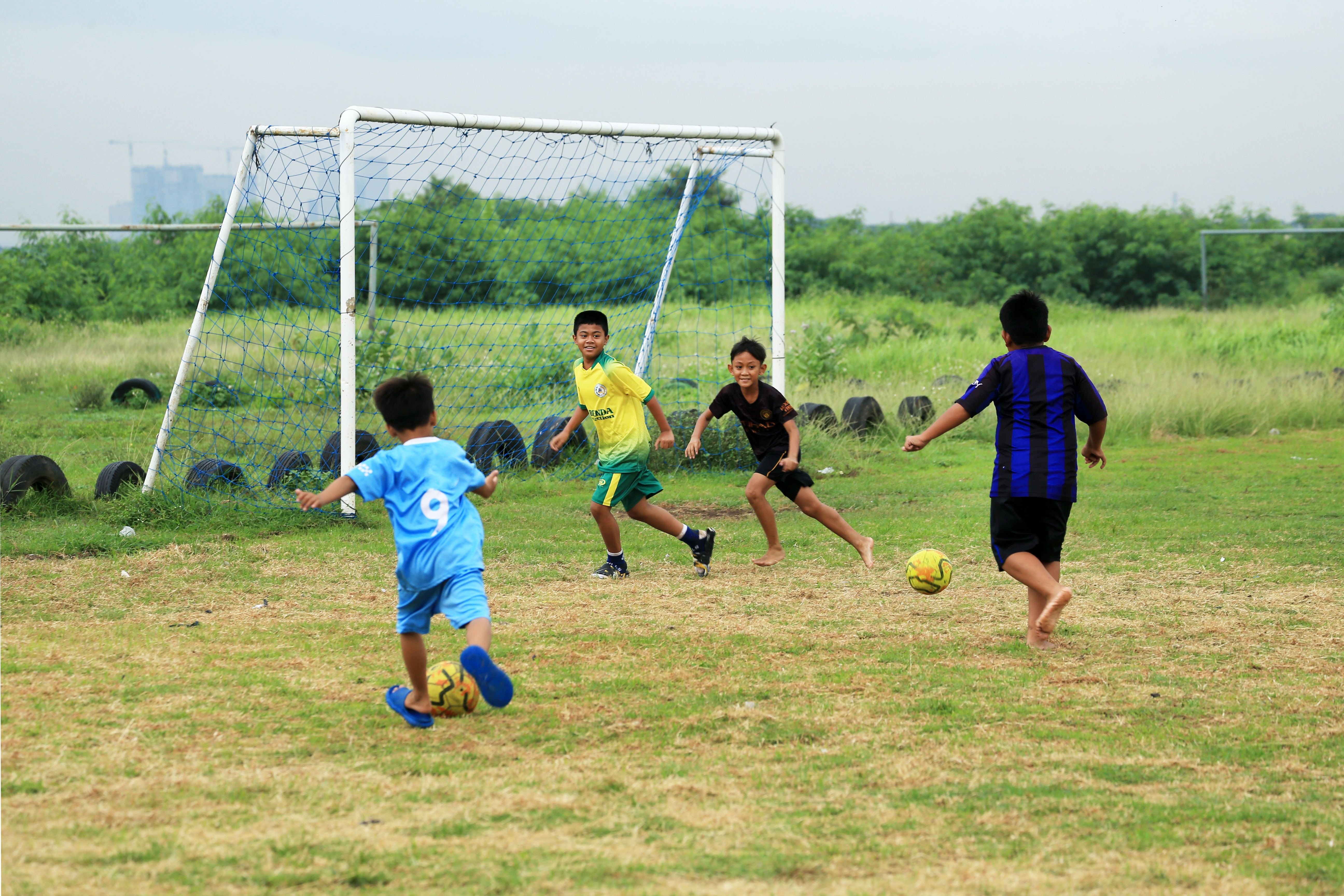 Children Playing Soccer on Grass Field Outdoors