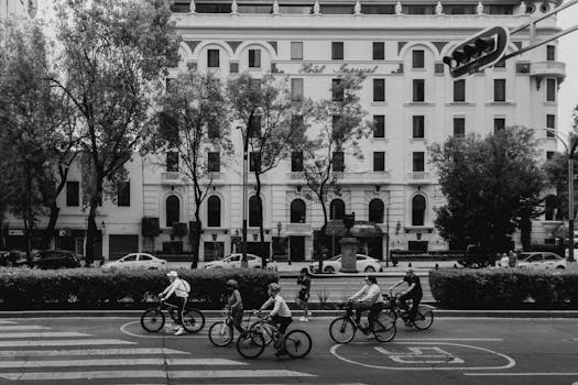 A group of cyclists biking past Hotel Imperial in Mexico City on a lively day.