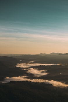 Peaceful aerial view of sunrise over misty mountains in Brazil, capturing nature's beauty.
