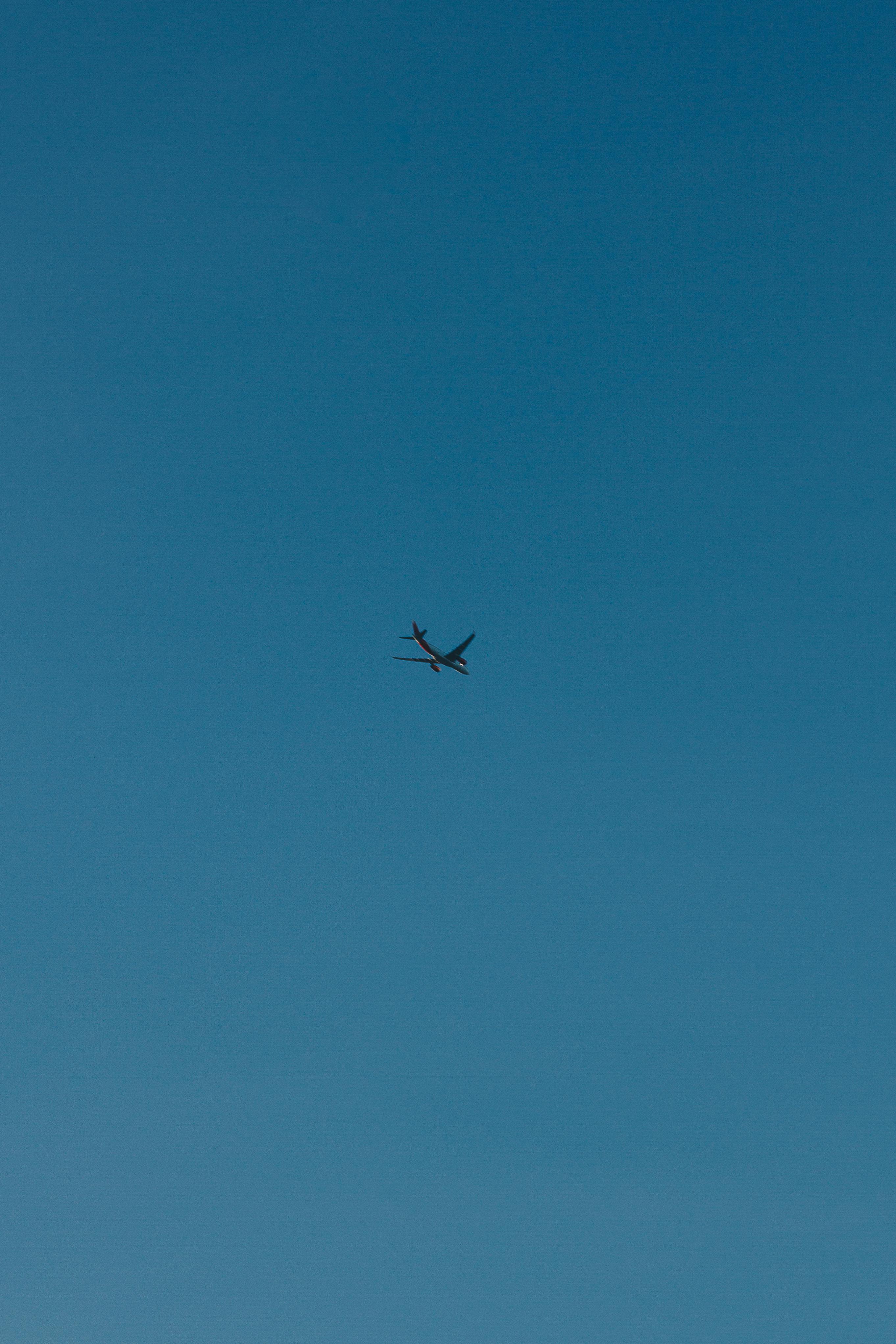 High altitude view of an airplane flying in a vibrant blue sky.