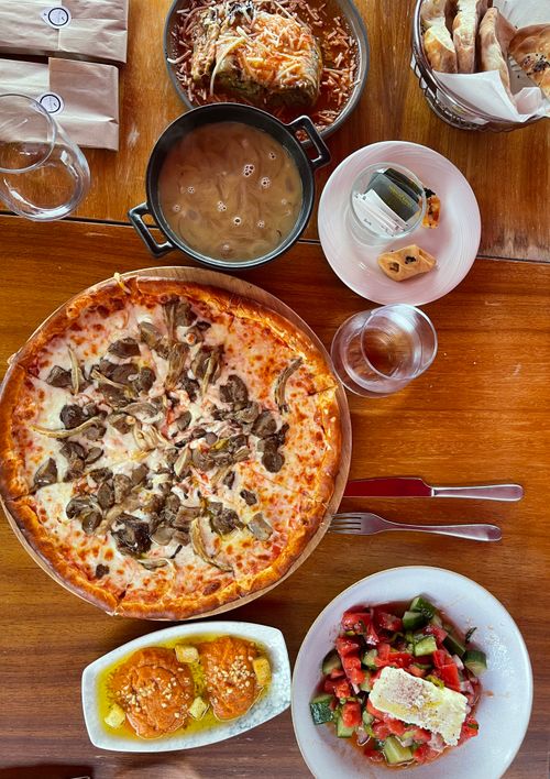Free Top view of a delicious Italian meal featuring pizza, lasagna, and salads on a wooden table. Stock Photo