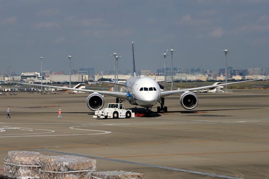 Wide-bodied aircraft on runway with cargo loading in urban airport setting.