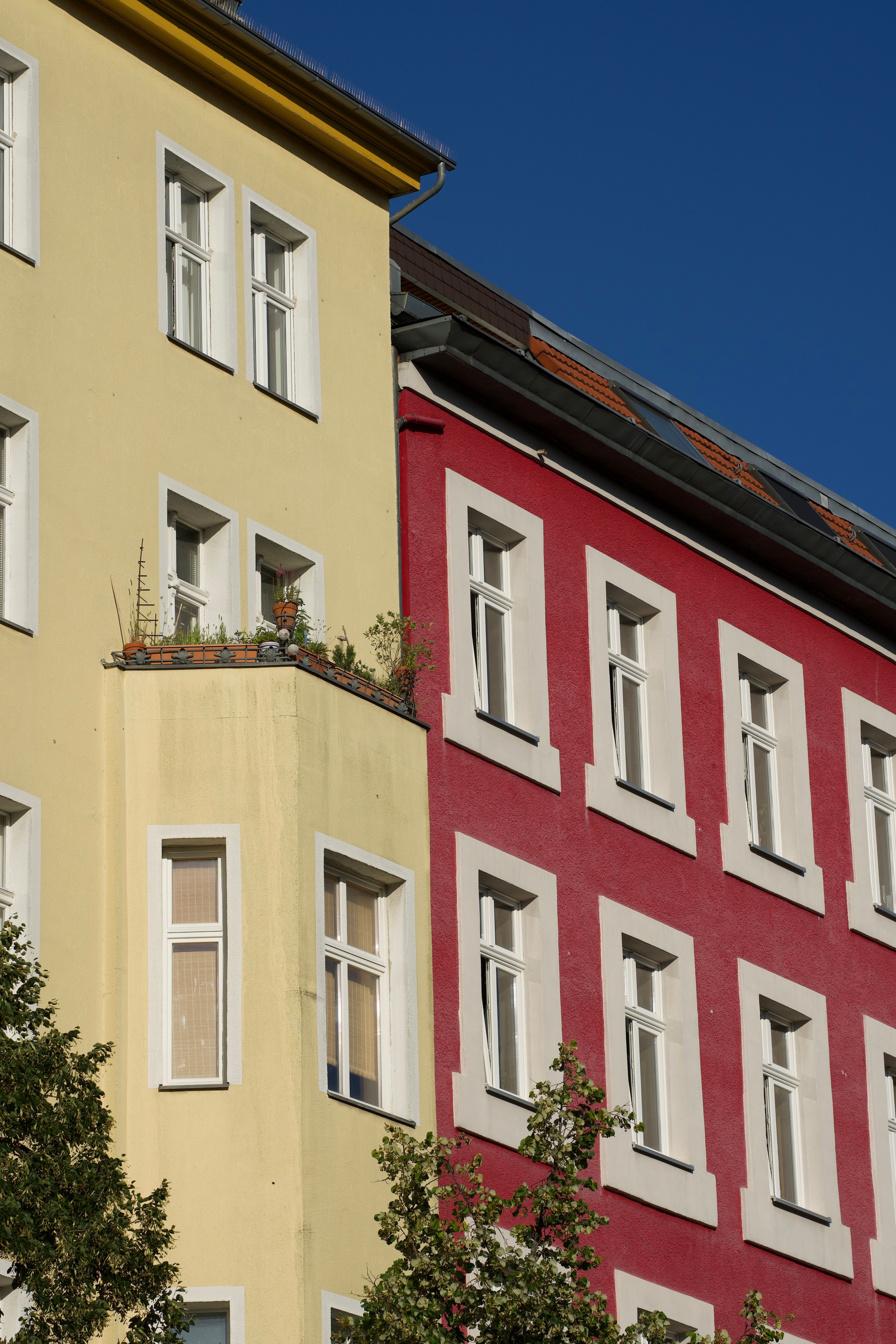 Free Vibrant facade of Berlin buildings with bright red and yellow colors under a clear blue sky. Stock Photo