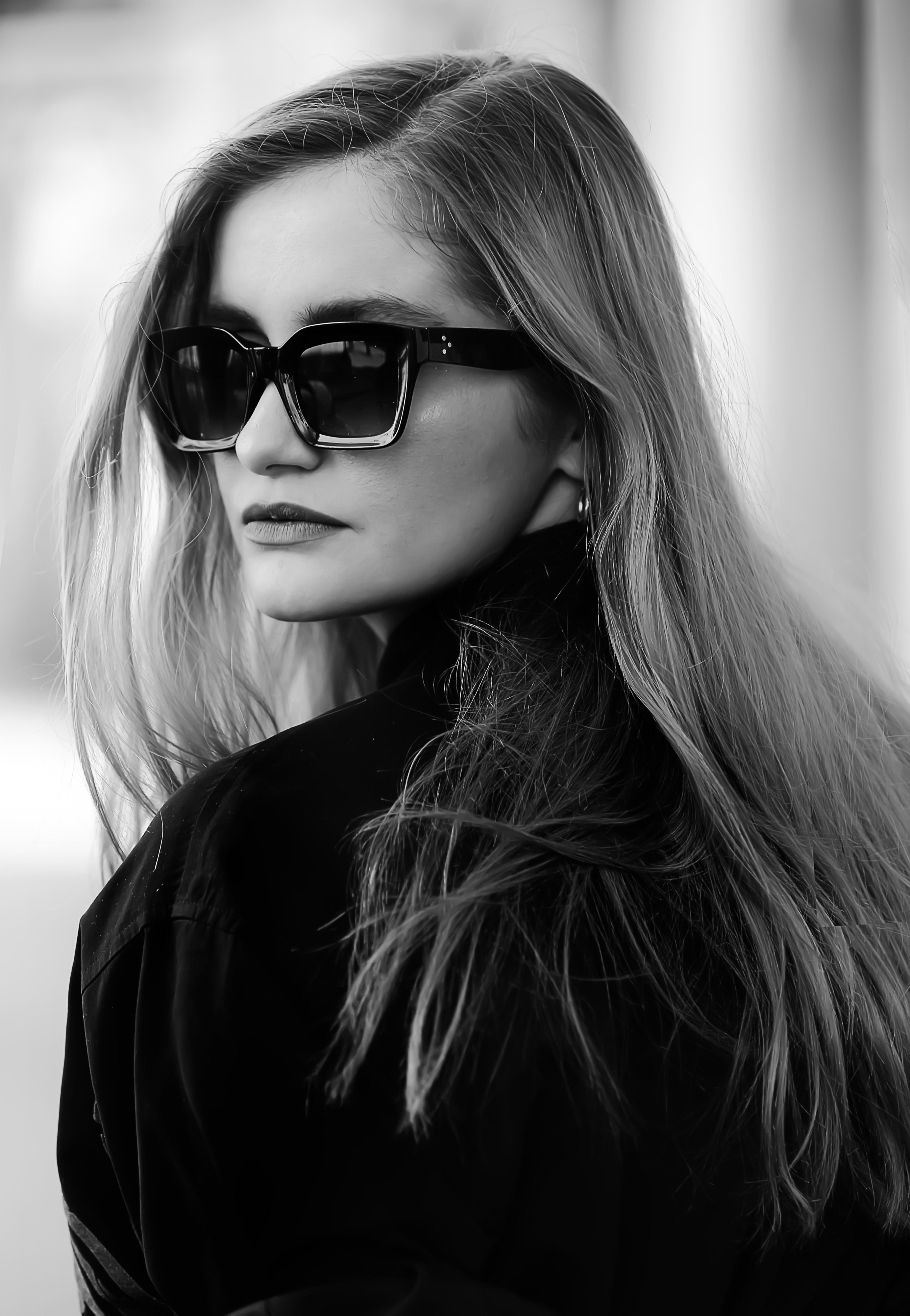 Elegant black and white portrait of a woman in sunglasses, exuding timeless fashion.