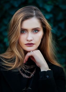 Close-up portrait of an elegant woman outdoors with striking eyes and soft light.