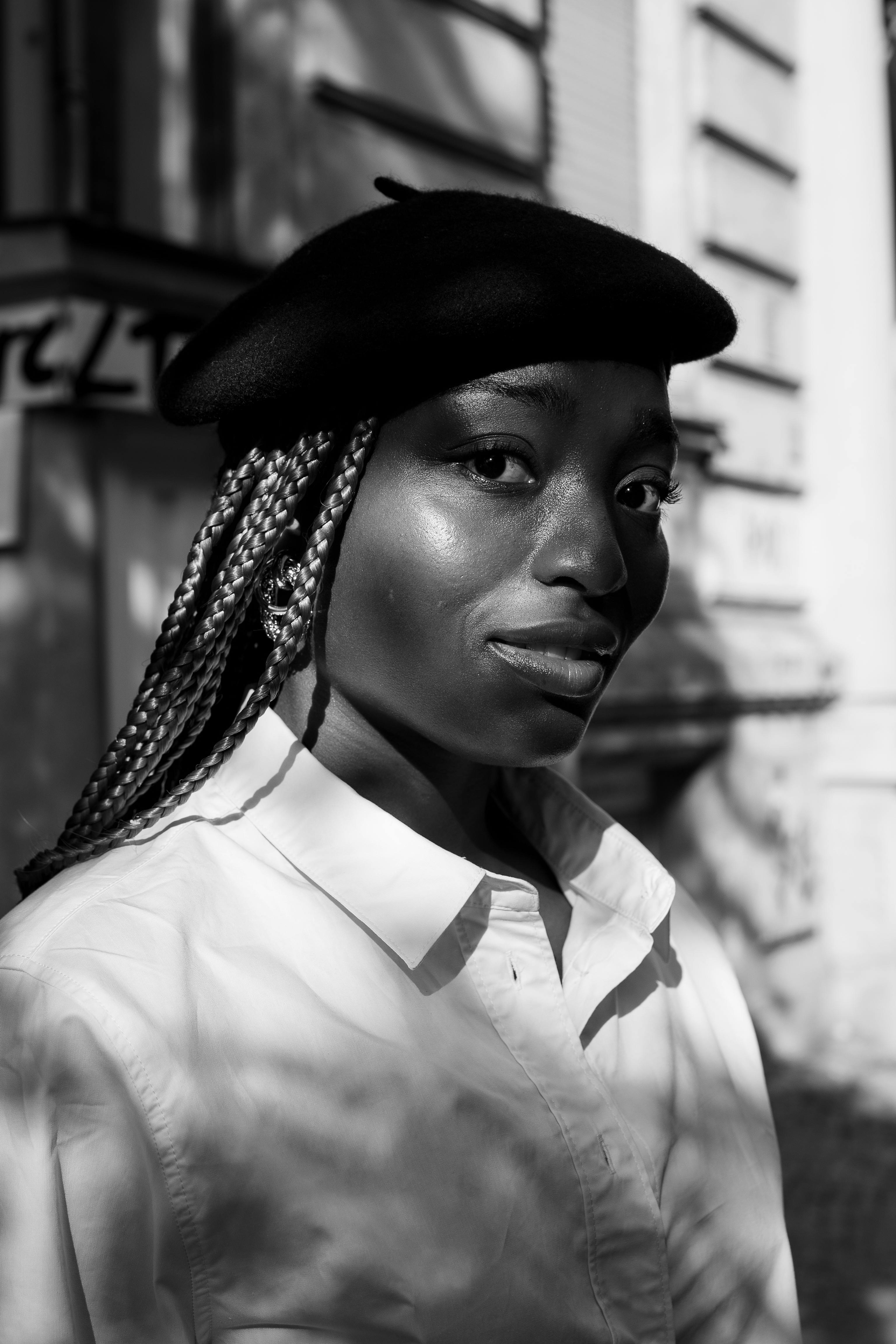 Striking black and white portrait of a woman with braids in Berlin, showcasing contrast and style.