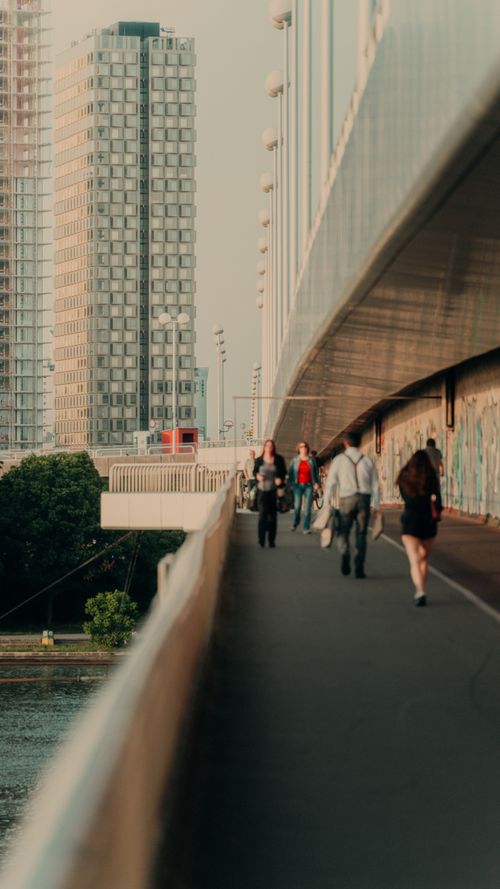 Free A city bridge walkway bustling with pedestrians against a backdrop of urban skyscrapers. Stock Photo