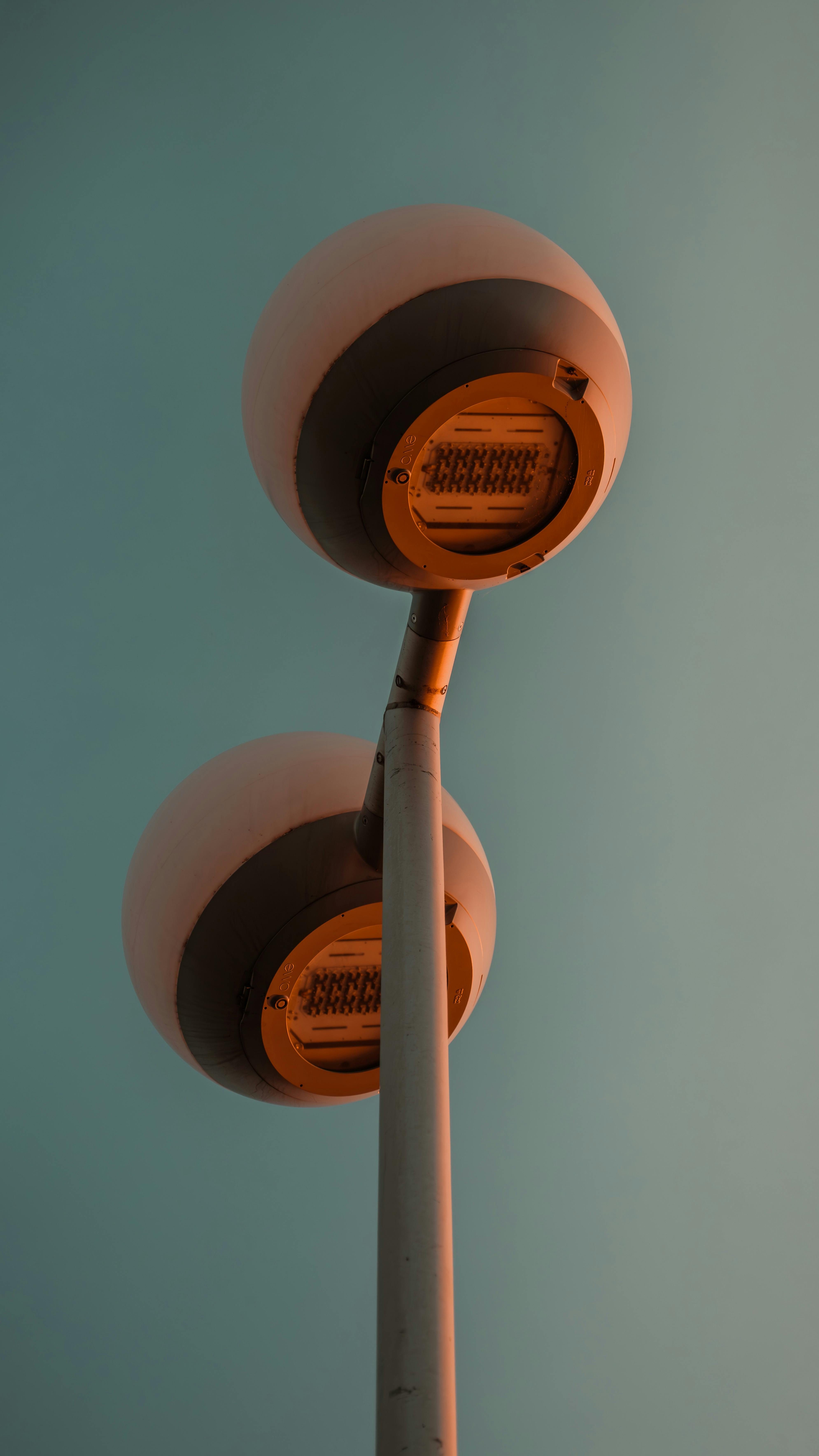 Gratis Due moderni lampioni illuminati da un cielo azzurro e terso al tramonto, emettono una luce calda. Foto a disposizione