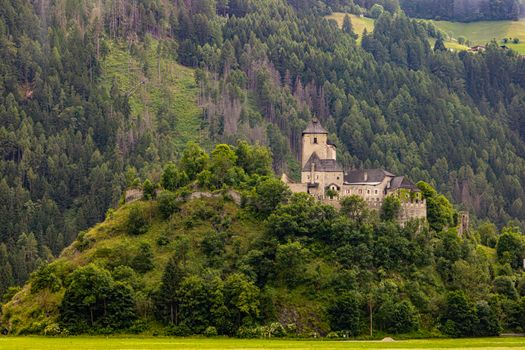 Serene view of a medieval castle nestled in the Austrian Alps surrounded by lush greenery.